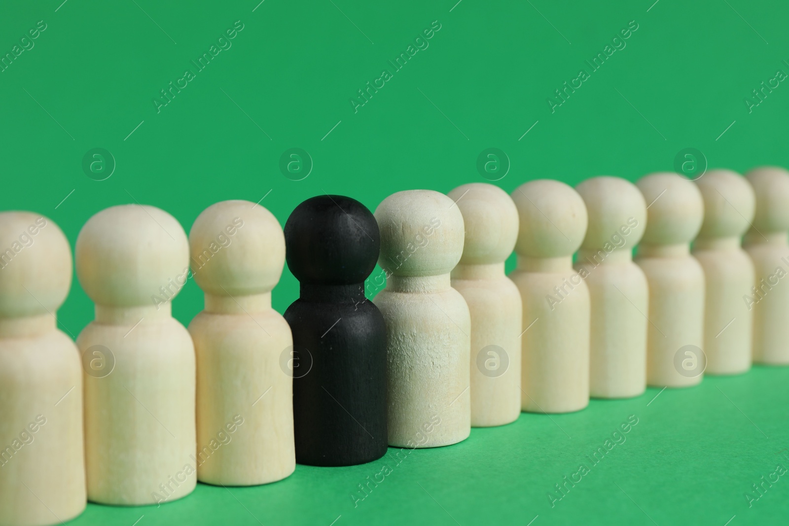 Photo of Black piece among wooden ones on green background, closeup