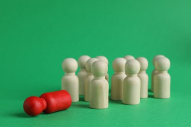 Red piece among wooden ones on green background