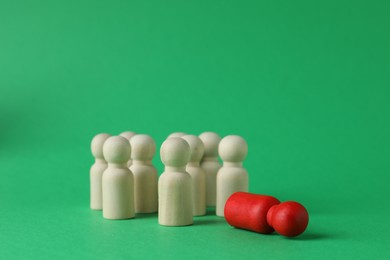 Red piece among wooden ones on green background