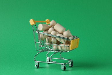 Photo of Wooden human figures in small shopping cart on green background