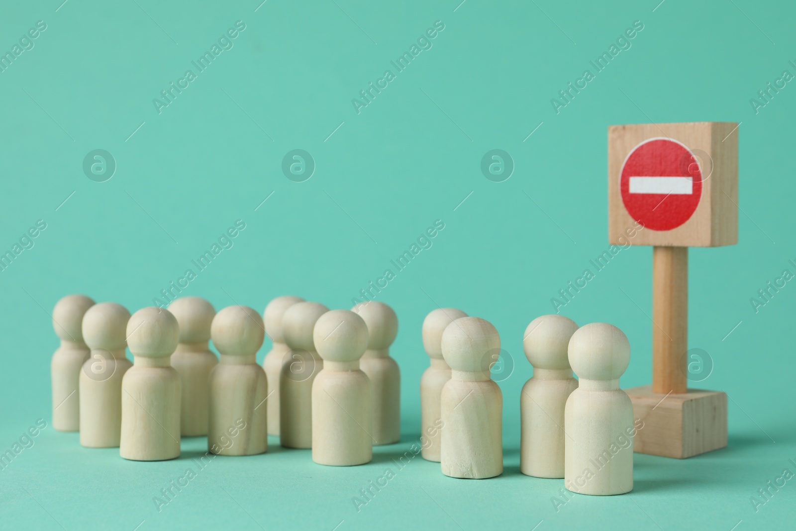 Photo of Wooden human figures and No entry road sign on turquoise background