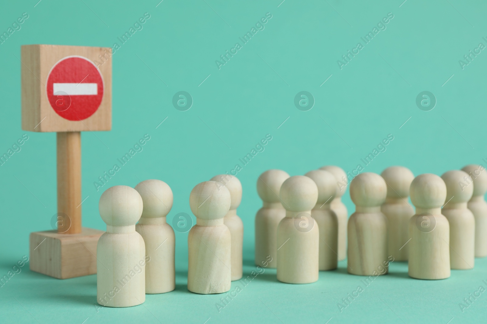 Photo of Wooden human figures and No entry road sign on turquoise background