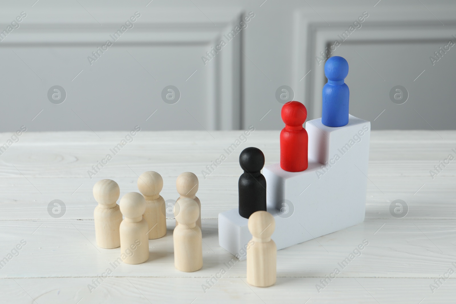 Photo of Stairs with group of different wooden human figures on white table