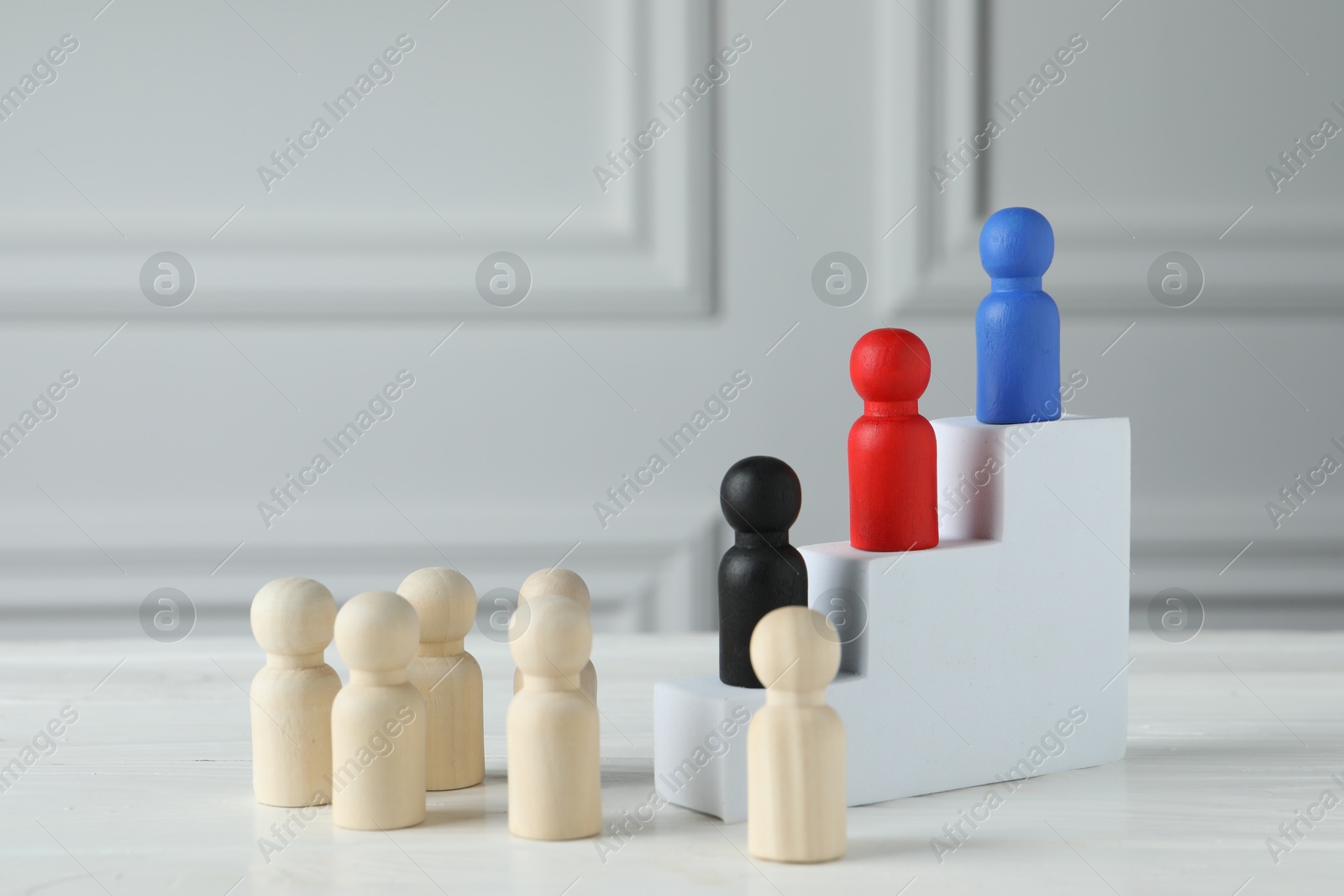 Photo of Stairs with group of different wooden human figures on white table