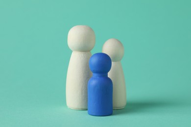 Group of wooden human figures on turquoise background