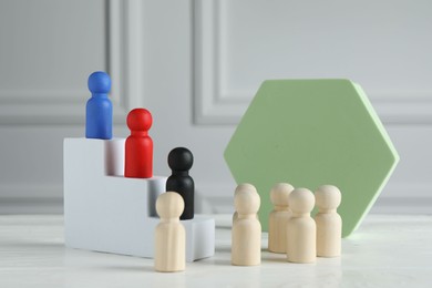 Stairs with group of different wooden human figures on white table