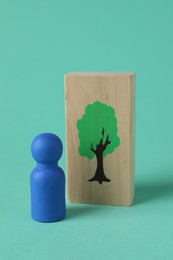 Photo of Blue human figure and drawn tree on wooden plank against turquoise background