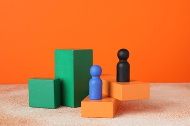 Photo of Different human figures on stands against orange background