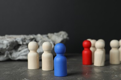 Different human figures on grey textured table against dark background