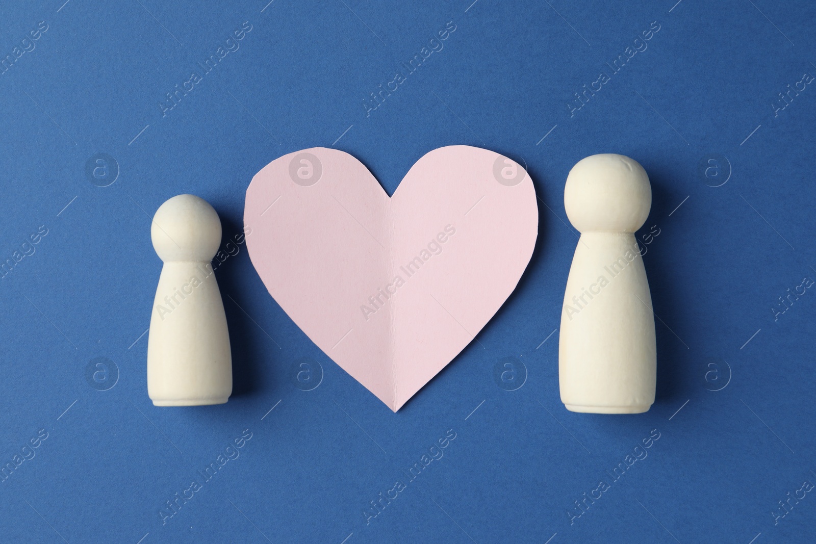 Photo of Human figures and paper heart on blue background, flat lay