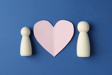 Photo of Human figures and paper heart on blue background, flat lay