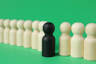 Black piece among wooden ones on green background, closeup