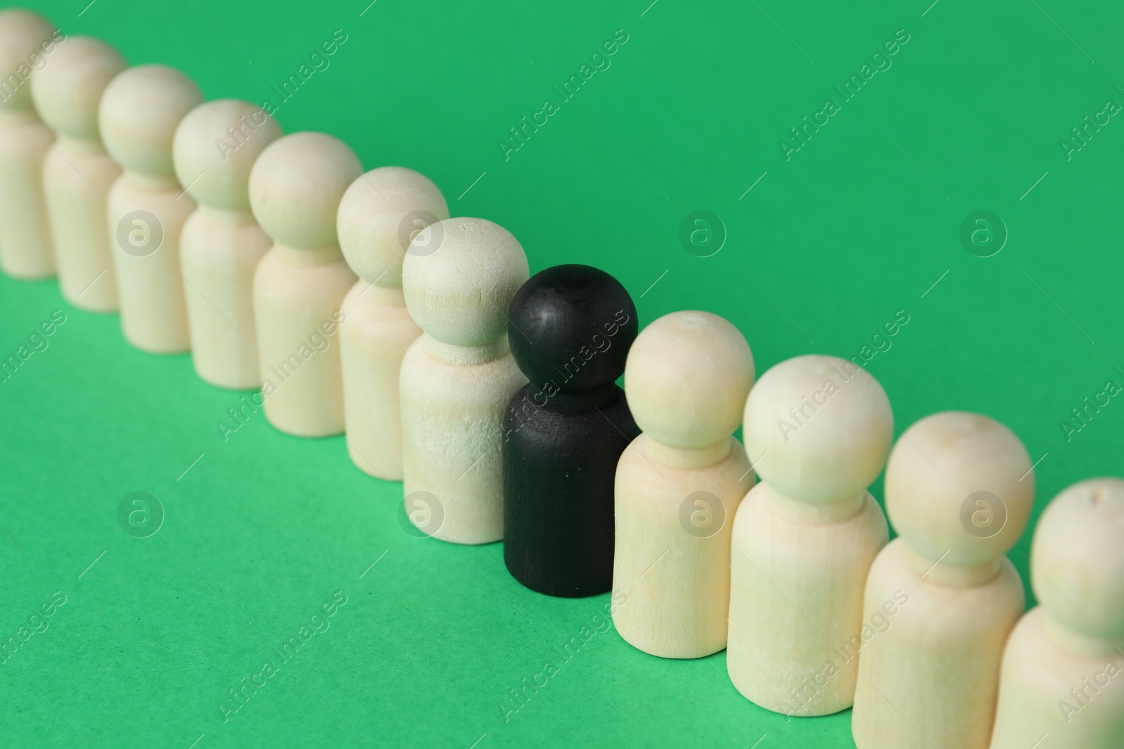 Photo of Black piece among wooden ones on green background, closeup