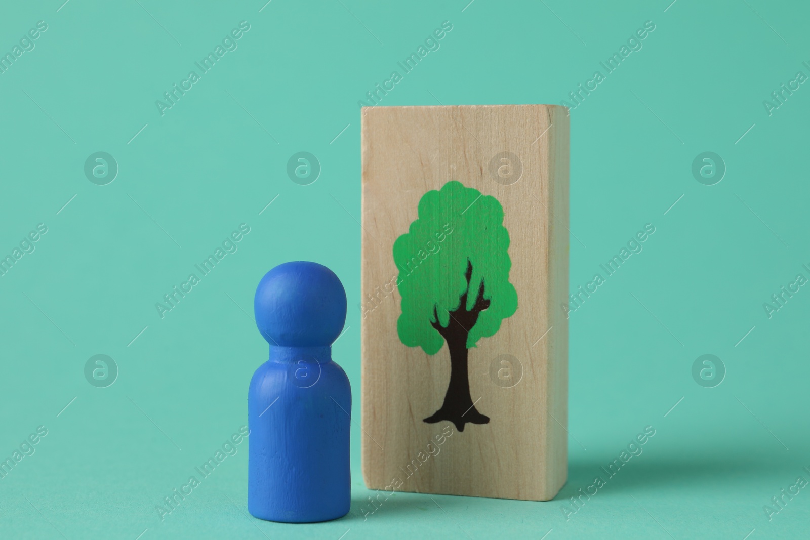 Photo of Blue human figure and drawn tree on wooden plank against turquoise background