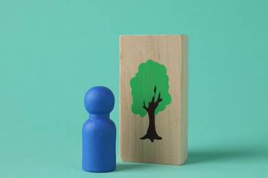 Blue human figure and drawn tree on wooden plank against turquoise background