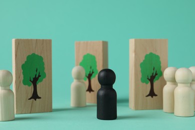 Photo of Black piece among wooden ones and drawn trees on planks against turquoise background