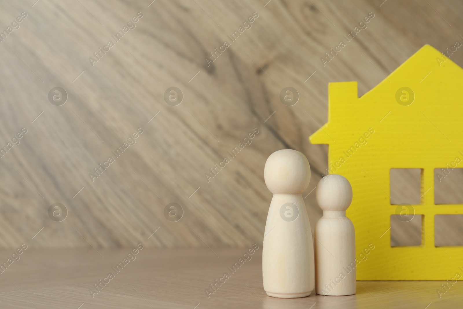 Photo of Wooden human figures and house model on table, space for text