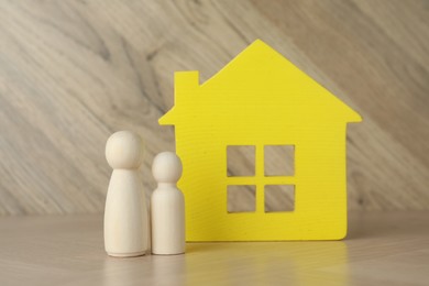 Photo of Wooden human figures and house model on table