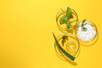 Photo of Petri dishes with green leaves and cosmetic products on yellow background, flat lay. Space for text