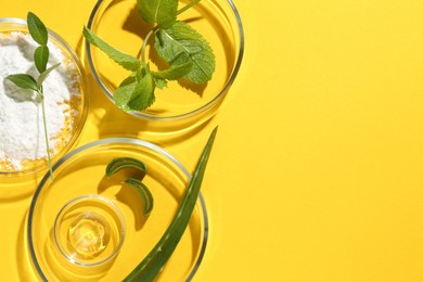 Petri dishes with green leaves and cosmetic products on yellow background, flat lay. Space for text