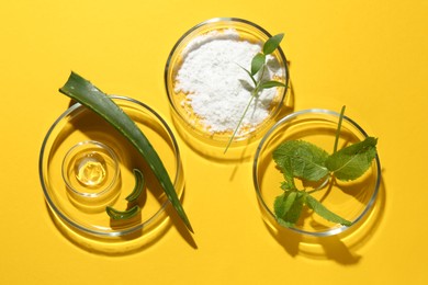 Photo of Petri dishes with green leaves and cosmetic products on yellow background, flat lay