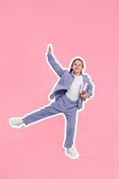 Smiling school child with books on pink background