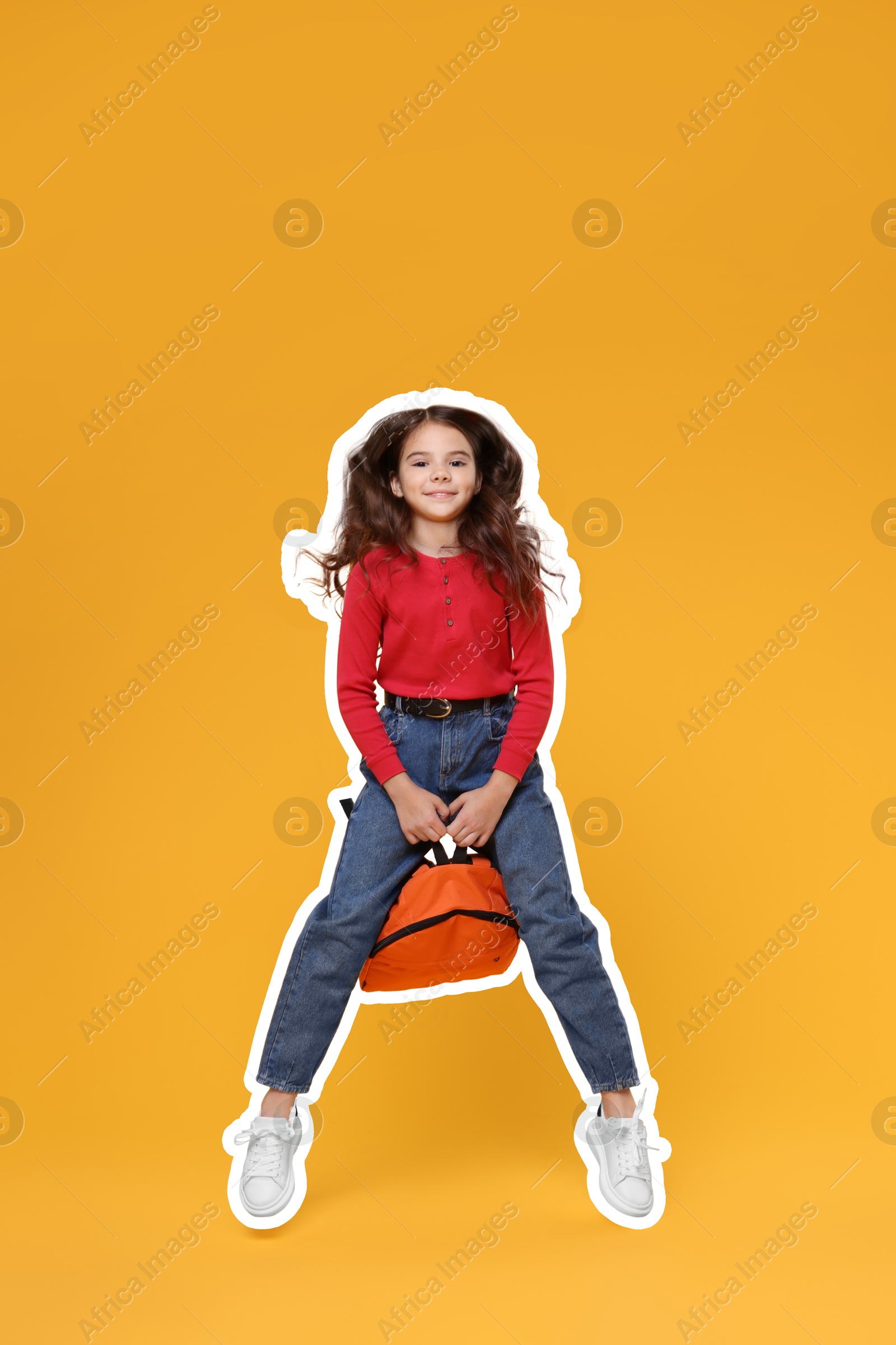 Image of Cute school child with backpack jumping on orange background