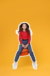 Cute school child with backpack jumping on orange background