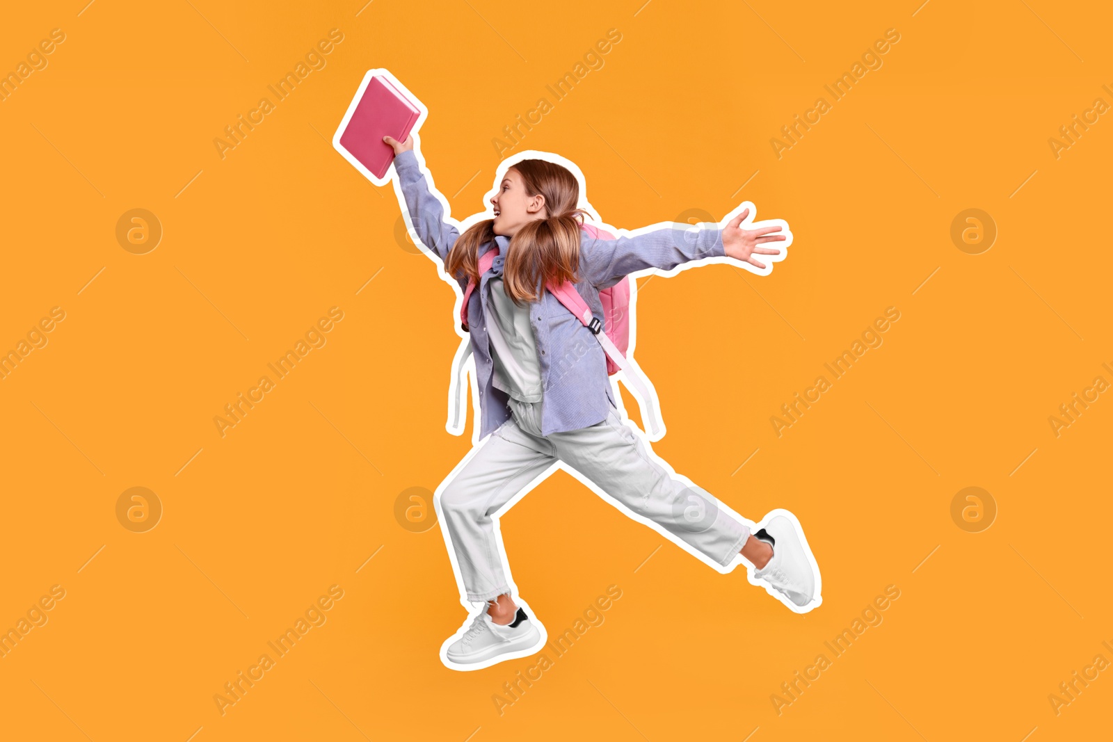 Image of Happy school child with book and backpack jumping on orange background