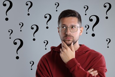 Thoughtful man and question marks on grey background