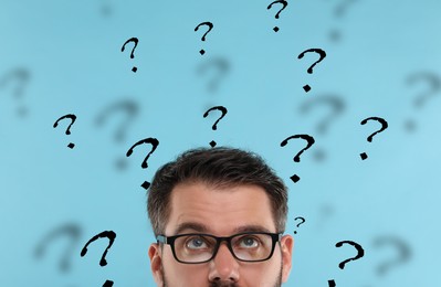 Man and question marks on light blue background, closeup