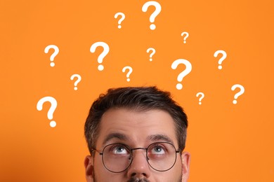 Man and question marks on orange background, closeup