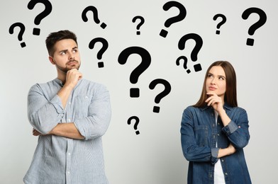 Image of Puzzled man and woman on light background. Question marks around them