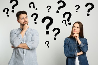 Puzzled man and woman on light background. Question marks around them