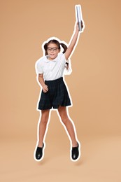 School child holding book and jumping on dark beige background