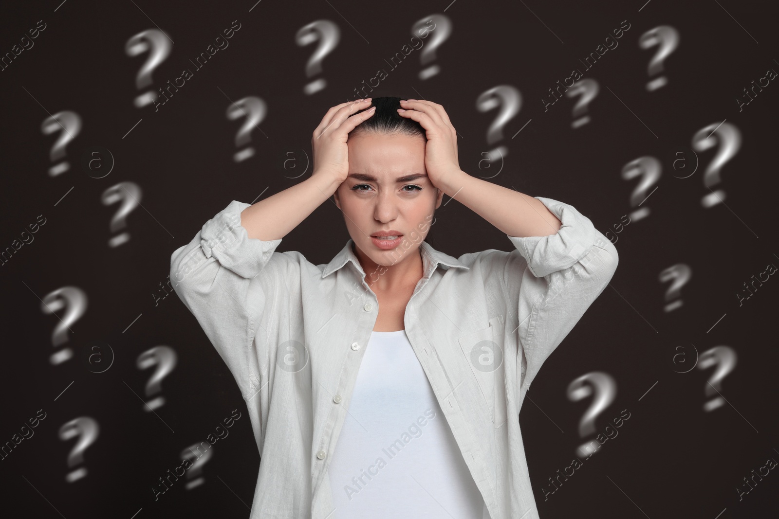 Image of Amnesia. Worried woman and question marks on dark brown background