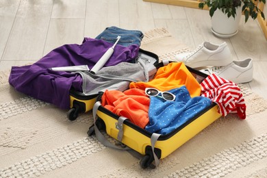 Photo of Open suitcase with traveler's belongings on floor