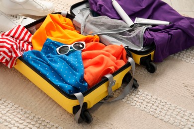 Open suitcase with traveler's belongings on floor