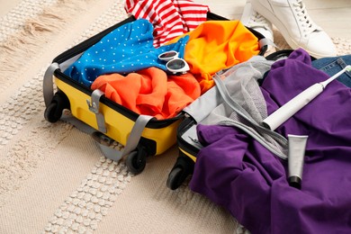 Photo of Open suitcase with traveler's belongings on floor