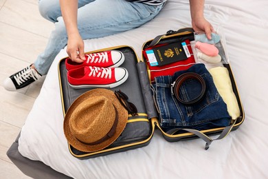 Man packing suitcase for trip on bed indoors, above view