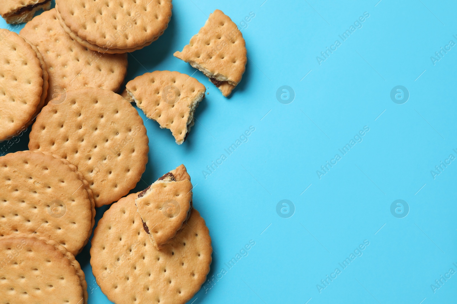 Photo of Tasty sandwich cookies on light blue background, top view. Space for text