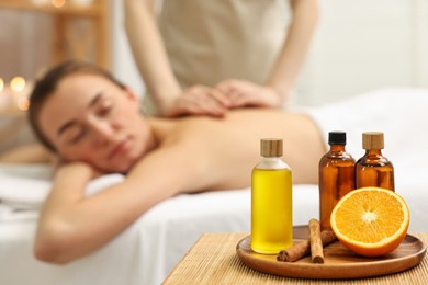 Photo of Aromatherapy. Woman receiving back massage in spa salon, focus on bottles of essential oils