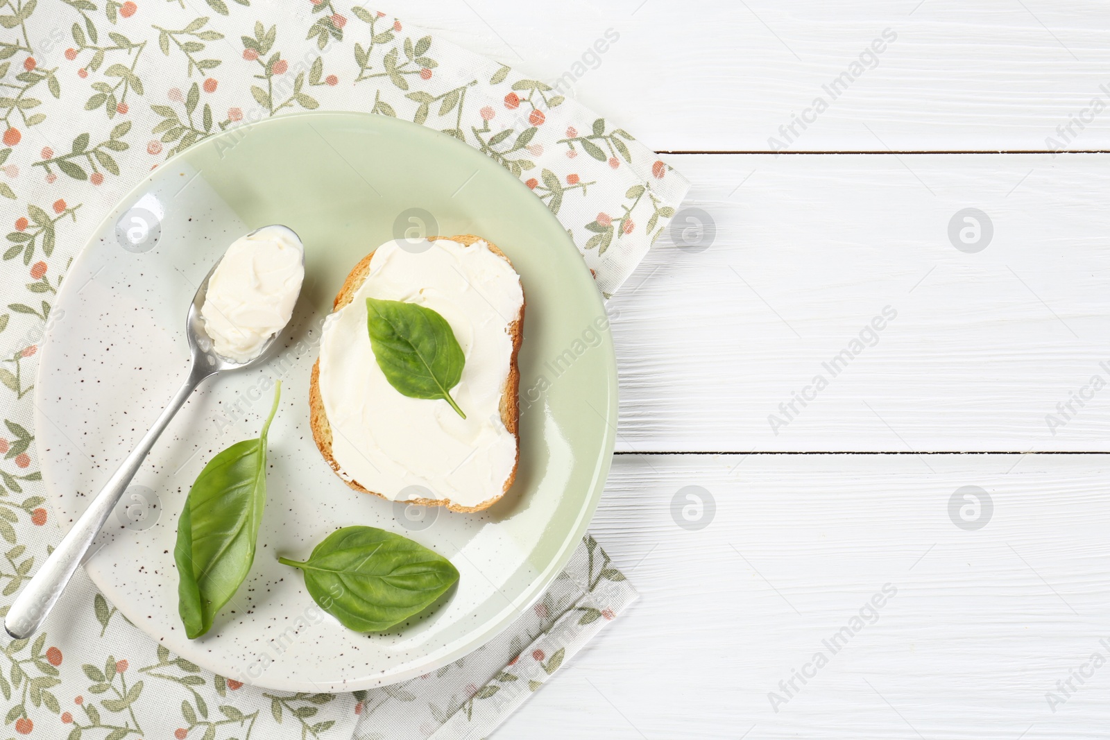 Photo of Delicious sandwich with cream cheese and basil leaves on white wooden table, top view. Space for text