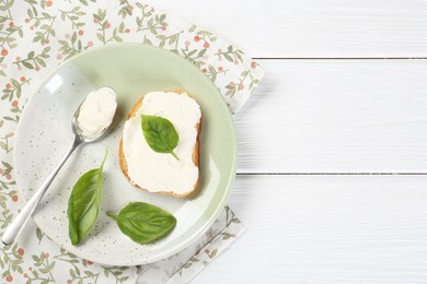 Delicious sandwich with cream cheese and basil leaves on white wooden table, top view. Space for text