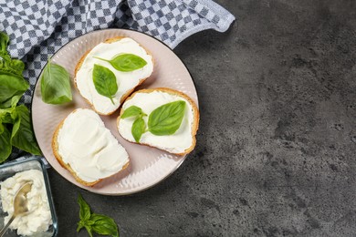 Photo of Delicious sandwiches with cream cheese and basil leaves on grey table, flat lay. Space for text