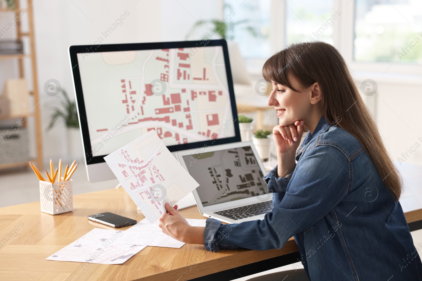 Photo of Smiling cartographer working with cadastral maps at table in office