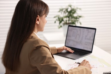 Photo of Cartographer working with cadastral map on laptop at white table in office