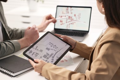 Cartographers working with cadastral maps at white table in office, closeup