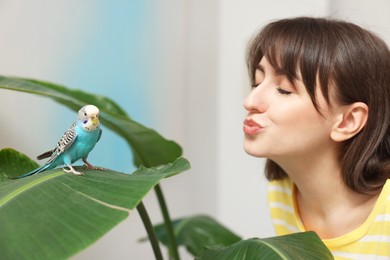 Woman with bright parrot indoors. Exotic pet