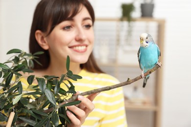 Woman with bright parrot indoors, selective focus. Exotic pet